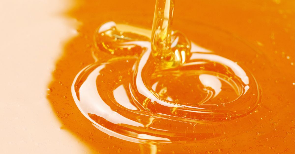 A macro closeup of honey being poured into a jar