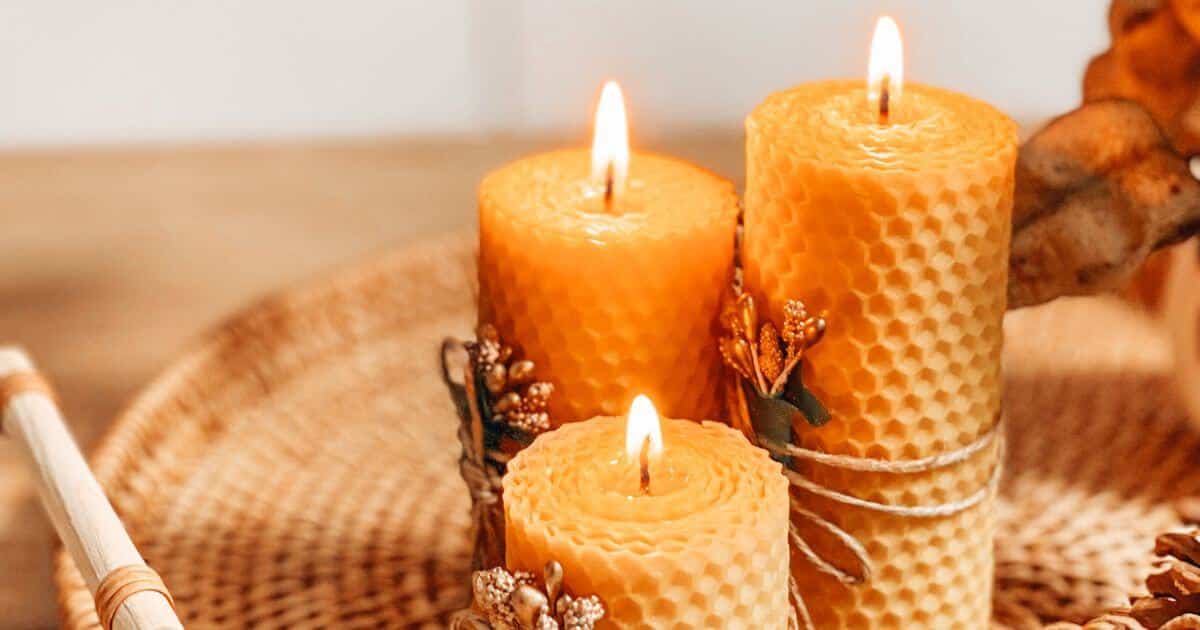 Three lit beeswax candles on a wicker tray