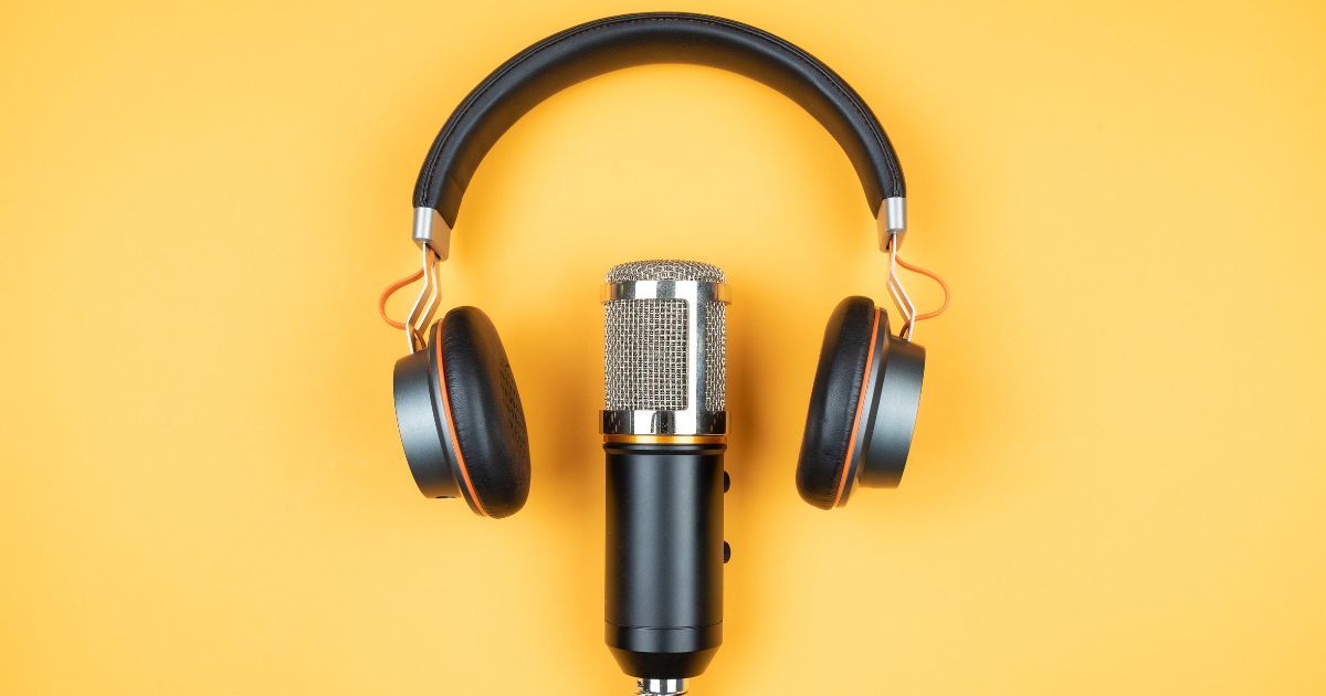 Podcast microphone and earphones on a plain yellow background