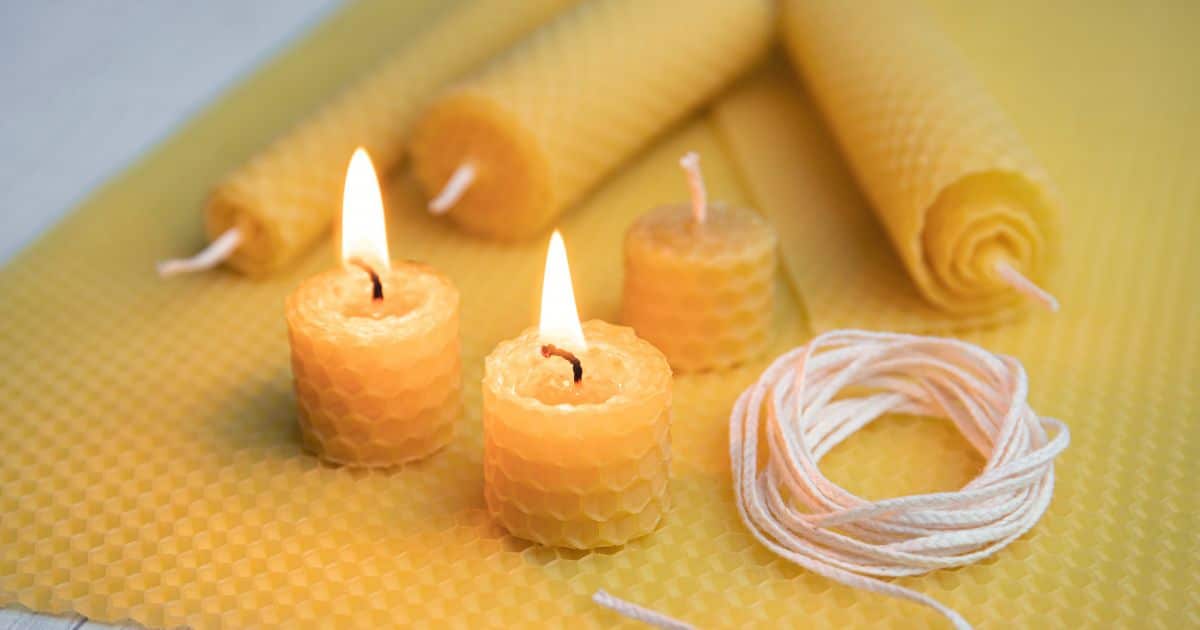 Four beeswax candles on top of a beeswax sheet; two candles are alight and two are not lit
